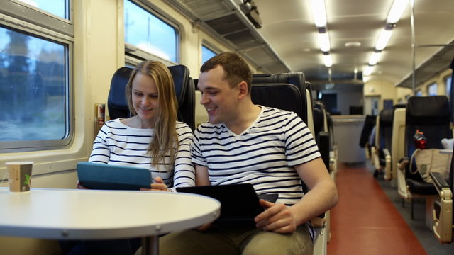 Woman with pad and man with laptop talking in the train