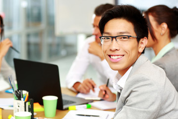 Portrait of a smiling businessman sitting in front of colleagues
