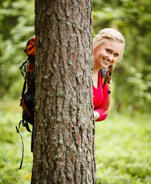 Young woman hiker behind a tree