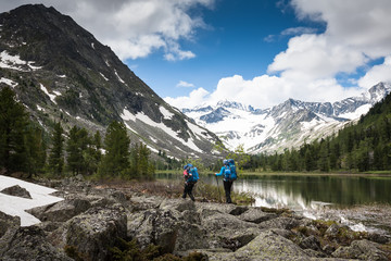 Fototapeta na wymiar Hikers are walking by mountain lake in Altai mountains, Russia