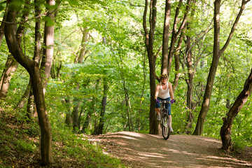 Woman is cycling in spring forest