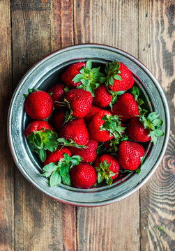 Strawberries in a bowl on wooden background