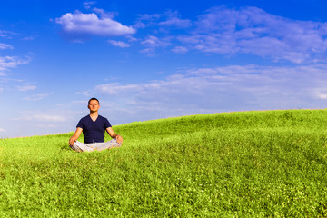 Handsome man meditating on the field.