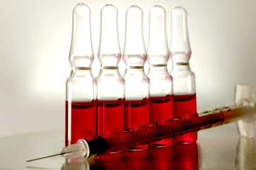 Five ampule with a red medicine and syringe, closeup