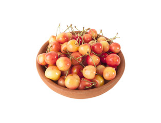 Red and yellow cherries in clay bowl on white