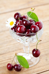 Fresh cherries in chrystal glass on wooden background