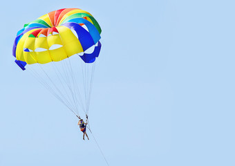 Девушка летит в голубом небе на красочном, разноцветном парашюте