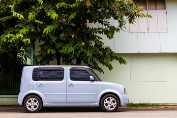 Van cars rectangular light blue four-door parked next to house - Powered by Adobe