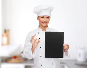 smiling female chef with black blank paper