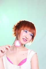 Girl with lollipop heart posing on light background