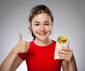 Girl eating big sandwich, showing Ok sign