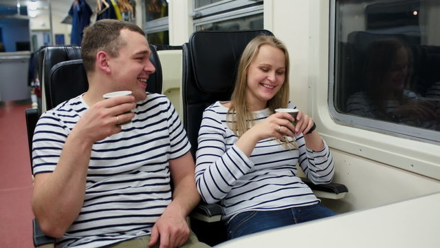 Man and woman talking and drinking tea or coffee in the train