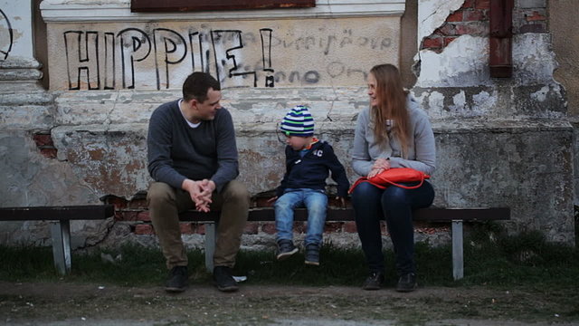 Parents and their child sitting on the bench near old grungy