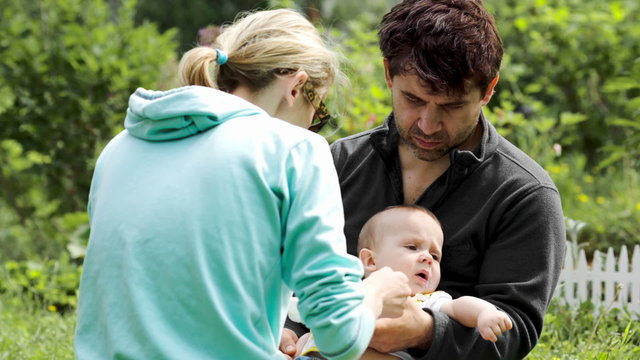 Young parents feeding a baby boy outdoor
