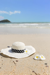 Straw hat and plumeria on the beach