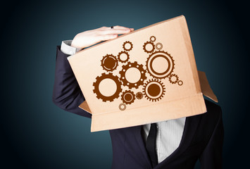 Businessman gesturing with a cardboard box on his head with spur