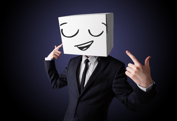 Businessman gesturing with a cardboard box on his head with smil