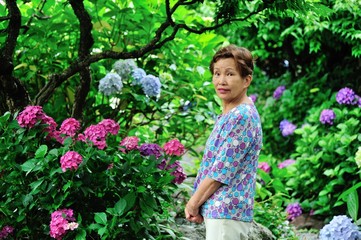 紫陽花の咲いている庭に立つ高齢の女性