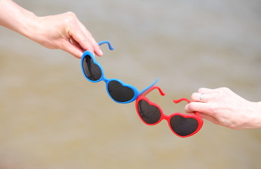 Hands with red and blue sunglasses shaped heart