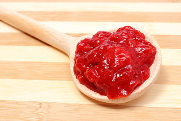 Strawberry jam with wooden spoon on cutting board