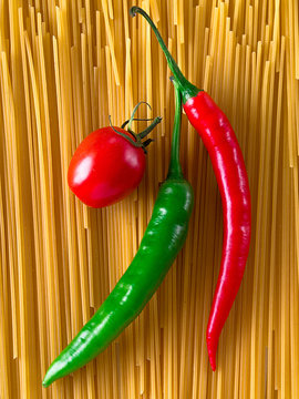 Rote Peperoni liegt auf ungekochter Pasta
