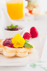 Crispy toast in flower shape with butter and raspberry jam. 