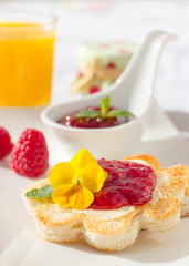 Crispy toast in flower shape with butter and raspberry jam. 