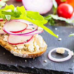 Open sandwich with feta cheese, radish and onion rings.