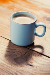 Cup of coffee on wooden table, toned