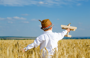 Cute little boy flying a toy plane in a wheatfield