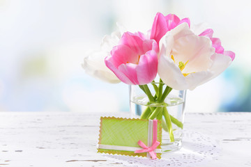 Beautiful tulips in bucket in vase on table on light background