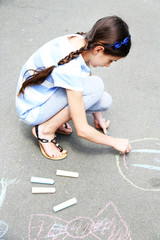 Cute girl drawing with chalk on asphalt