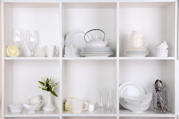 Fototapeta na wymiar Different white clean dishes on wooden shelves