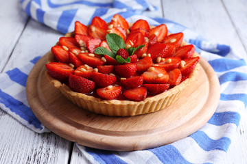 Strawberry tart on wooden tray, on color wooden background