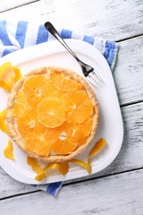 Homemade orange tart on plate, on color wooden background