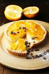 Homemade orange tart with coffee grains on wooden background