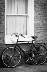 Old bike by the window of a cottage black and white picture
