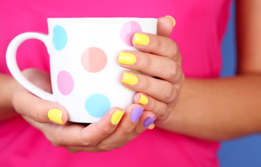 Woman with stylish colorful nails holding mug, close-up,