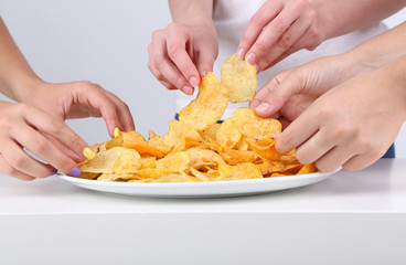 Hands of people take chips from bowl