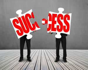 Businessmen standing and holding two puzzles with SUCCESS