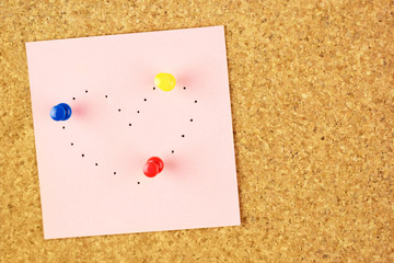 Sticker with heart shaped with pinholes on corkboard