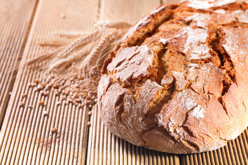 Fresh bread with wheat on the wooden background