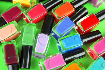 Group of bright nail polishes, on green background