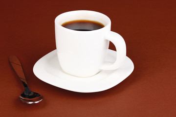 A cup of strong coffee on brown background
