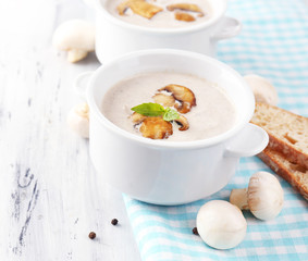 Mushroom soup in white pots, on napkin,  on wooden background