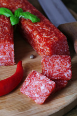 Tasty salami sausage and spices on wooden background