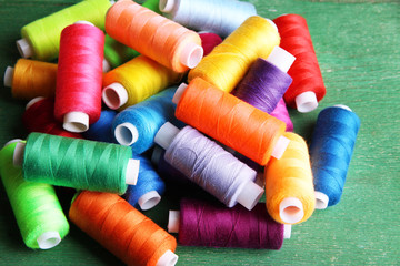 Multicolor sewing threads on wooden background