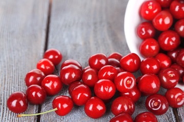 Sweet cherries in mug on wooden background