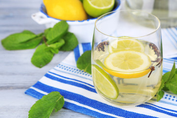 Fresh summer drink with lime and cloves in glass and jug,