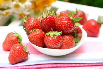 Ripe sweet strawberries in bowl on table in garden